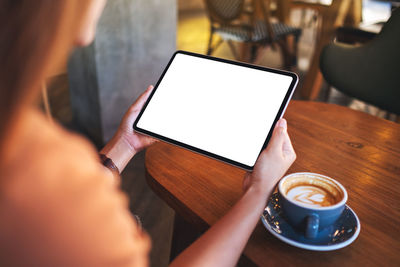 Mockup image of a woman holding digital tablet with blank white desktop screen