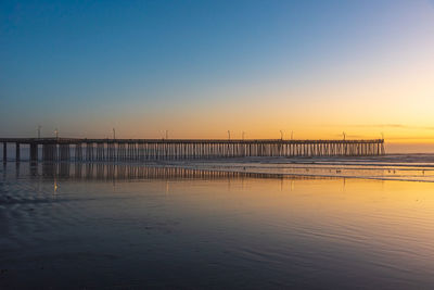 Pier on sea against clear sky during sunset