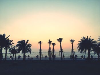 Silhouette palm trees on beach against sky during sunset