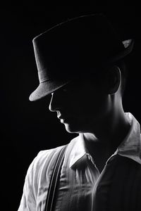 Close-up of a man wearing hat over black background