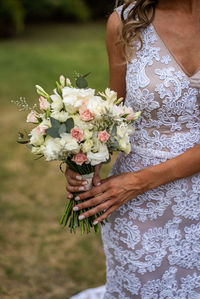 Midsection of woman holding white flowering plant