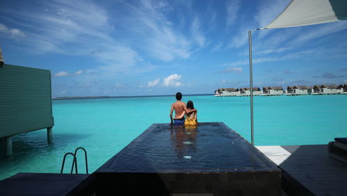 Rear view of couple standing in infinity pool