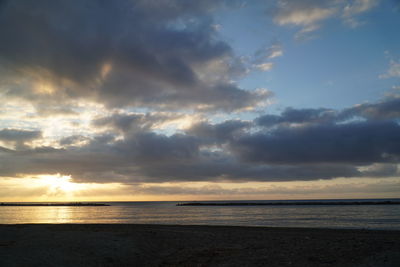 Scenic view of sea against dramatic sky during sunset