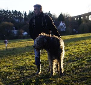 Man standing with irish wolfhound on grassy field