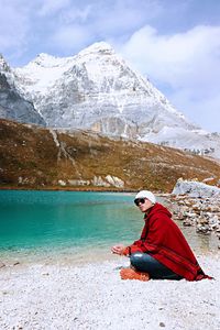 Side view of man sitting on riverbank