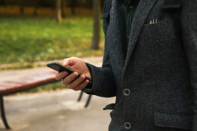 Midsection of man using mobile phone
