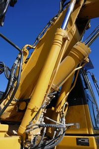 Low angle view of earth mover against clear sky