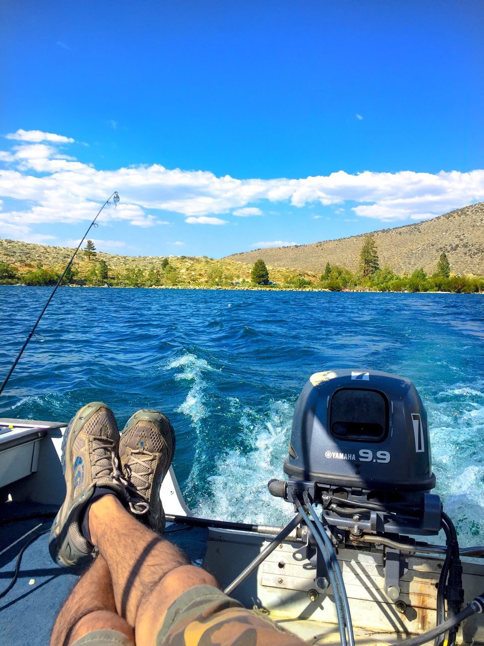 water, personal perspective, mode of transport, sky, part of, boat, blue, lifestyles, cropped, leisure activity, cloud - sky, nature, day, outdoors, beauty in nature, unrecognizable person, scenics, cloud, sailing, mountain, tranquility, tranquil scene