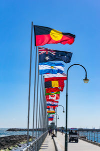 St kilda pier with rows of national flags with australian aboriginal flag