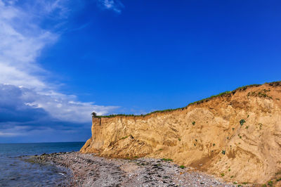 Scenic view of rocks on beach against blue sky