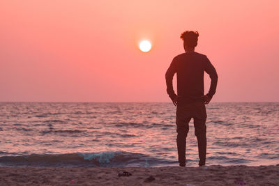 Silhouette man standing on beach against sky during sunset