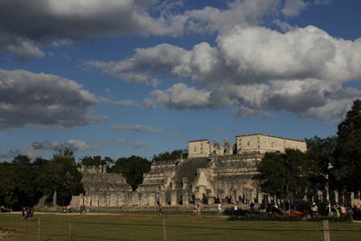 People at temple against cloudy sky