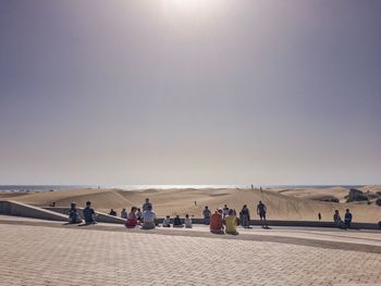 People sitting on footpath by beach