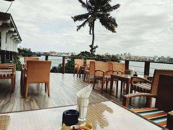 Chairs and table by sea against sky