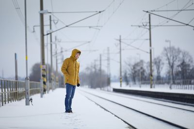 Snowy railroad station during frosty day. man standing on platform and waiting for delayed train.