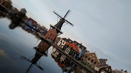 Traditional windmill by building against sky