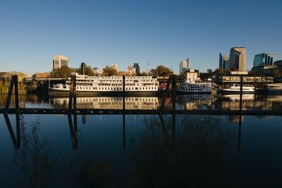 Reflection of buildings in river against clear sky