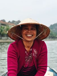 Portrait of smiling woman standing against river