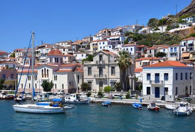 Sailboats moored on canal by buildings in city against clear blue sky