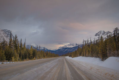 Road amidst snowcapped mountains against sky during winter