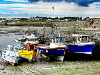 Boats moored at harbor against sky