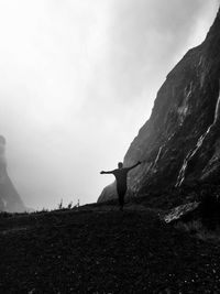 Rear view of man with arms outstretched while standing on mountain