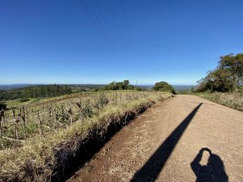 Shadow of man on road against clear blue sky