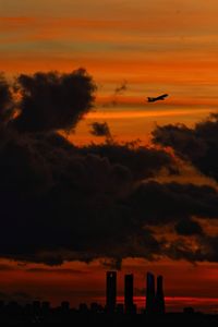 Silhouette bird flying in sky during sunset