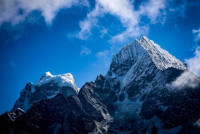 Low angle view of snowcapped mountains against blue sky