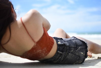 Midsection of woman lying on beach