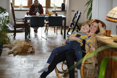 Mother with child and dog at home on rocking chair having fun time together. parent with kid