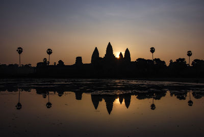 Reflection of silhouette buildings in lake at sunset