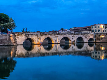 Arch bridge over river against blue sky