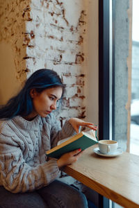 Young woman using phone while sitting on table