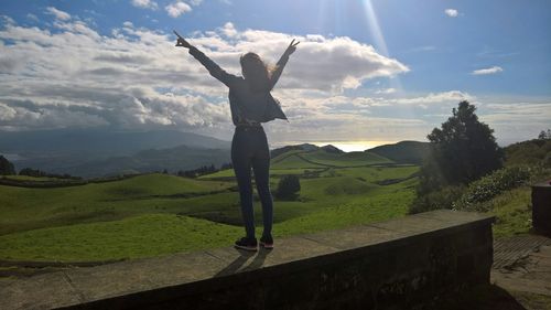 Woman with arms raised in landscape