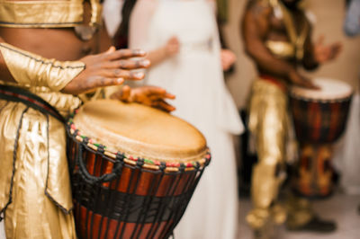 Midsection of performers playing drums