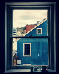 Buildings against sky seen through glass window