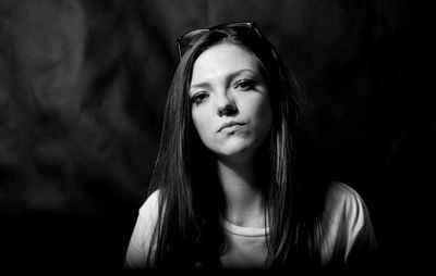 Close-up portrait of young woman against black background