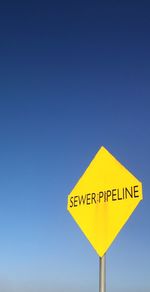 Low angle view of information sign against clear blue sky