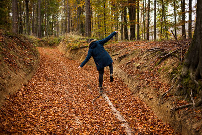 Full length of man jumping on road in forest