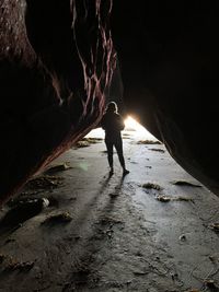 Rear view of silhouette woman standing in cave