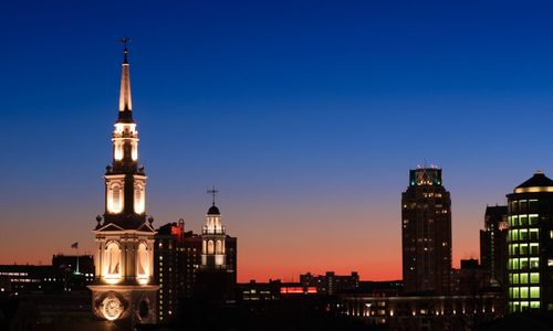 Illuminated buildings against clear sky at sunset