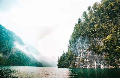 Scenic view of sea by mountain against sky