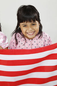 Smiling girl with red and white striped textile looking away against wall