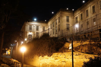 Illuminated street amidst buildings at night