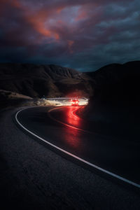 Light trails on road against sky at night