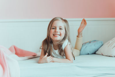 Portrait of smiling girl lying on bed at home