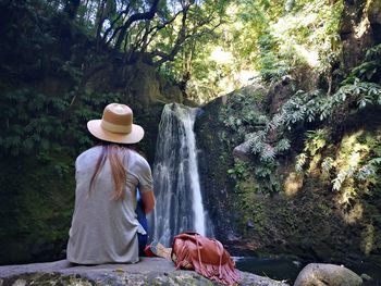 Woman wearing hat by trees in forest