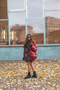 Portrait of young woman standing against building 