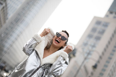 Laughing woman in sunglasses against buildings